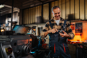 A metallurgist examining a metal ring with a tool next to a lathe machine.