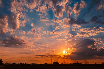 Sunset with a dramatic sky and overland high voltage lines near Tabertshausen, Deggendorf, Bavaria,...
