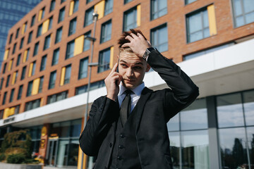 Amid the urban hustle, a distressed young man in business attire engages in a conversation on his mobile phone, revealing the weight of his troubles and concerns.