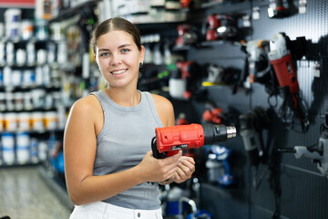 Beautiful young woman chooses and buys industrial hair dryer in local hardware store