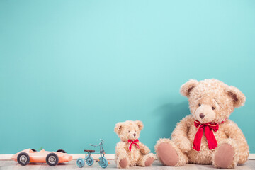 Teddy Bears, toy tricycle and old vintage plastic car front mint blue wall background. Mother or father with baby concept. Retro style filtered photo