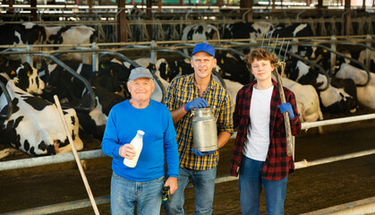 Continuity of generations - portrait of farmers of different ages against the backdrop of a cowshed