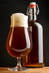 Craft beer brewing at home. Cap beer bottles with glass of beer on wooden table.
