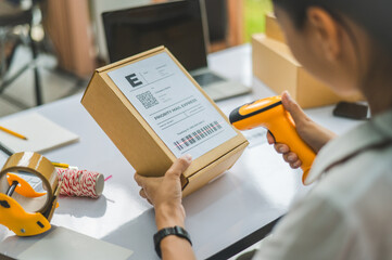 online small business owner scans a barcode-labeled parcel with a barcode scanner to verify a customer's order before it is delivered to the customer. - obrazy, fototapety, plakaty