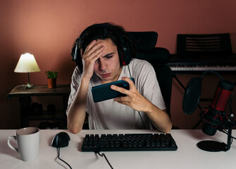Long-haired professional gamer or streamer, around 20 years old,  intensly focused with an expression of frustration and defeat, he clutches his head because a critical mistake or loss in the game. 