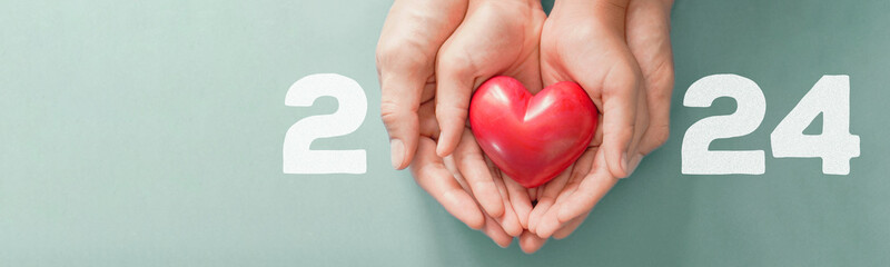 2024 with hands holding Red heart , Happy New Year for heart health insurance, donation and medical...