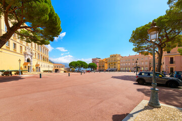 The Place du Palais atop the Rock of Monaco with the Prince's Palace of Monaco on the left, entrance to the Old Town on the right, and the harbor and hills in view, in Monte Carlo Monaco. - obrazy, fototapety, plakaty