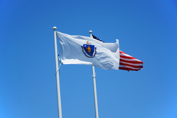 Massachusetts state flag and USA flag waving on the pole in the wind