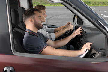 Driving school. Happy student passing driving test with examiner in car at parking lot