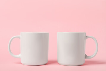 Two white ceramic mugs on pink background