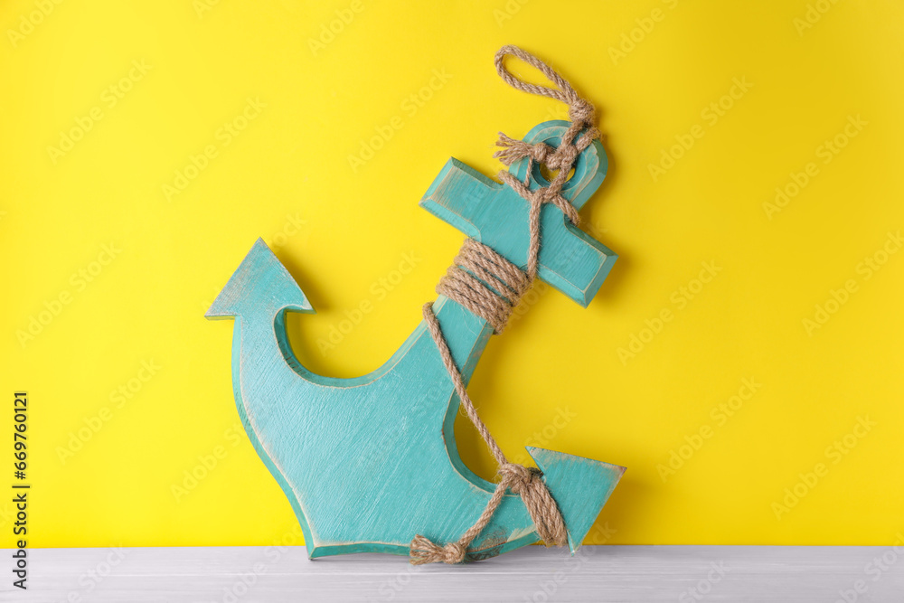 Sticker Anchor with hemp rope on white wooden table near yellow wall