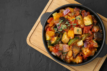 Dish with tasty ratatouille on black table, top view. Space for text