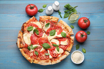 Delicious Caprese pizza and ingredients on blue wooden table, flat lay