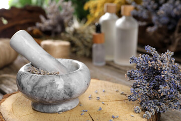 Mortar with pestle and lavender flowers on wooden table, closeup. Medicinal herbs