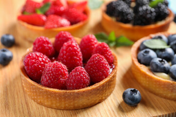 Tartlet with fresh raspberries on wooden board, closeup. Delicious dessert