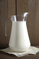 Jug of fresh milk on wooden table