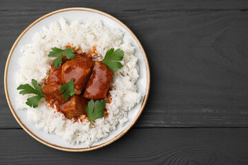 Delicious goulash with rice on grey wooden table, top view. Space for text