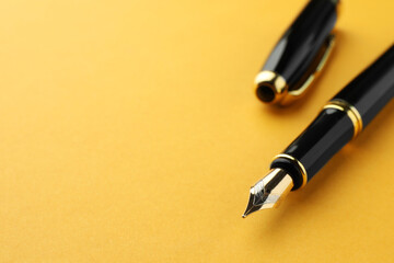 Stylish fountain pen with cap on yellow background, closeup. Space for text