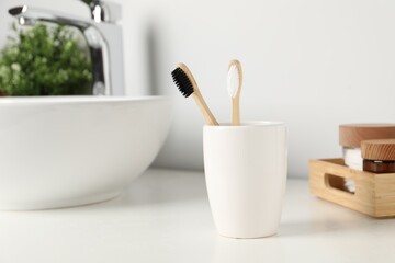 Fototapeta na wymiar Bamboo toothbrushes on white countertop in bathroom