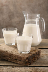 Jug and glasses of fresh milk on wooden table