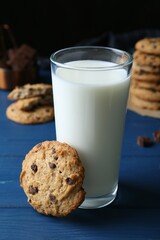 Tasty chocolate chip cookies and glass of milk on blue wooden table