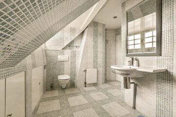 a bathroom with blue and white mosaic tiles on the walls, along with a sink and toilet in the corner