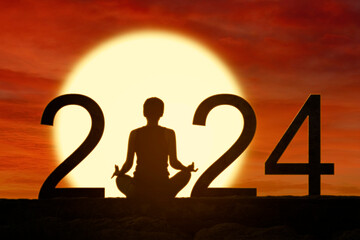 Silhouette of a woman exercising yoga while doing meditation with 2024 new year