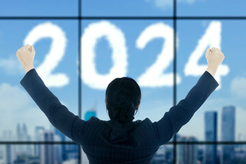 businesswoman standing on the glass window with cloud shaped 2024 new year