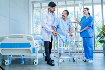 A Muslim male doctor and nurse help a patient who is doing physical therapy and is practicing walking with a walking stick.