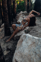 Beautiful woman at the stone between palms in the evening 