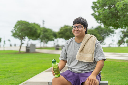 Fat man with a bottle of water after training outdoors
