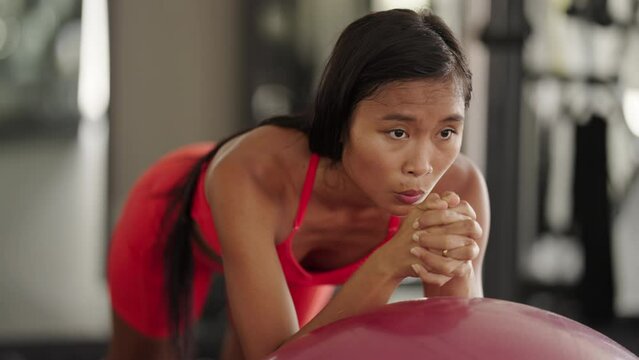 Young asian female doing plank exercise on medicine ball at gym for core stability workout