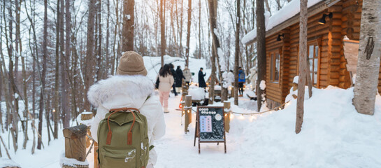 Woman tourist Visiting in Furano, Traveler in Sweater sightseeing Ningle Terrace Cottages with Snow...