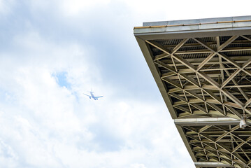 Fototapeta premium Civil aviation aircraft flying over modern buildings in the city