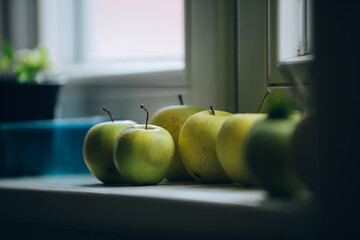 Green apples placed by a window where light comes in