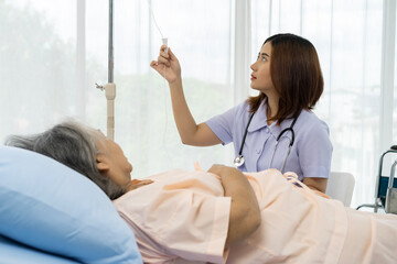 Fototapeta premium A nurse or caregiver for an elderly patient is adjusting the normal rate of medical saline given to the patient.