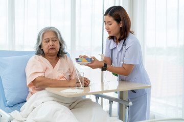 Fototapeta premium A nurse cares for and feeds an elderly Asian patient but she has anorexia.