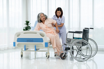 A nurse carries an elderly Asian patient from a wheelchair onto a bed after taking him for an x-ray of his leg injured in an accident.
