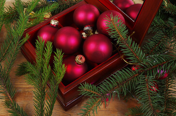 Colored Christmas balls in a festive box surrounded by spruce branches.