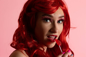 Fototapeta premium Beautiful Young Women with Scarlet Red Hair Posing with Valentine's Decor in a Hot Red Jumper