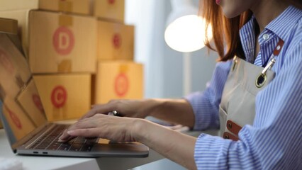 A young woman who has started a small online store is inspecting boxes of products and parcels in preparation for delivery.
