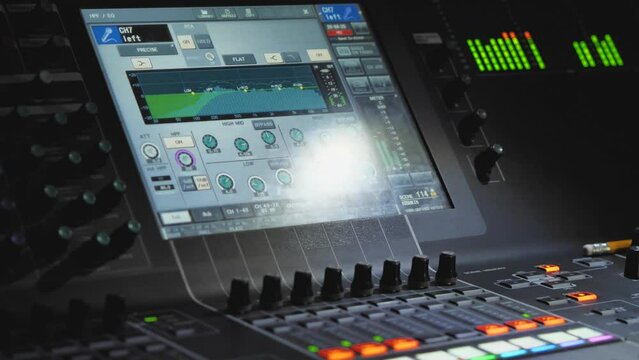 LED screen with running EQ track on mixing console. Close-up of a professional modern audio mixer. Recording studio. Production of music, podcasts and more