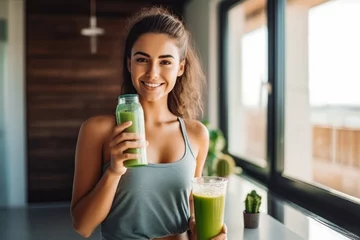 Poster Attractive young latina woman drinking her detox juice after workout, beautiful athletic female drinking green juice at home © VisualProduction