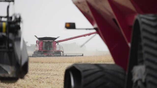 Combine Harvester Harvesting Grain Crops from a Farm Field on a Dusty Day