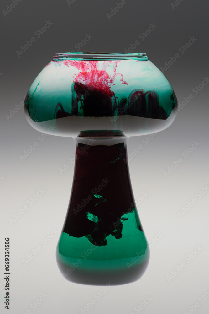 Wall mural Mushroom shape glass jar with colorful food coloring dripping into water making unique patterns