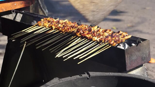 People bake sate. Sate is one of traditional indonesian food which served with peanut sauce