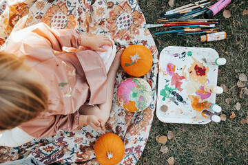 4-year-old girl painting a colorful pumpkin
