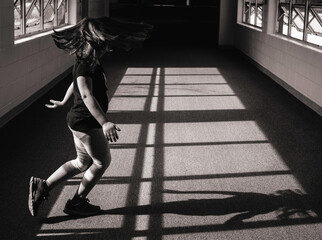 Young girl dancing with shadow in hallway