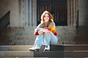 Pretty smiling teen girl sitting on cathedral steps, backlit.