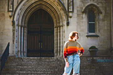Fototapeta na wymiar Beautiful teen girl standing in front of cathedral steps, backlit.